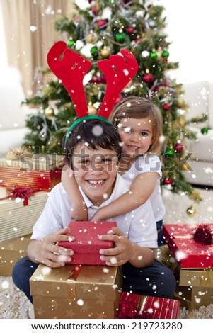 Composite image of Happy brother and sister celebrating Christmas with snow falling