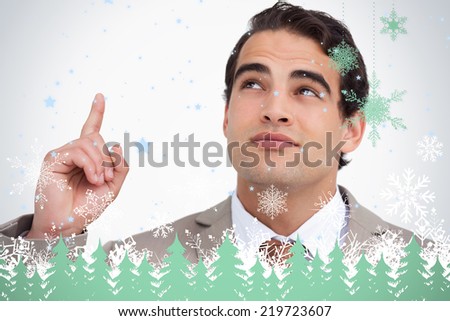 Close up of salesman looking and pointing up against snowflakes and fir trees in green
