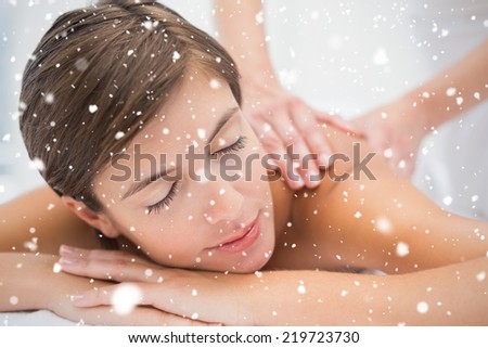 Attractive woman receiving back massage at spa center against snow falling