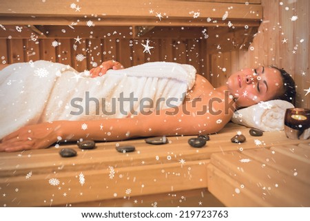 Peaceful brunette woman lying in a sauna against snow falling