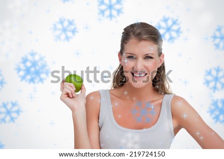 Composite image of woman holding an apple against snowflakes