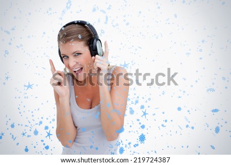 Cheerful woman dancing while listening to music against snow falling