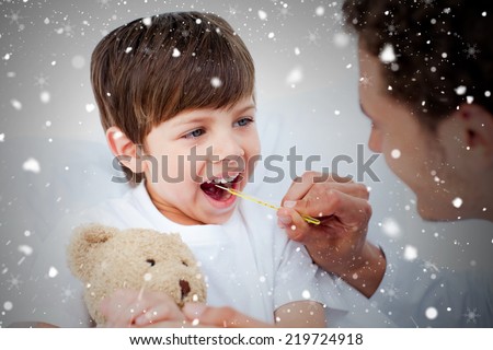 Composite image of positive doctor taking little boys temperature against snow falling