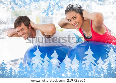 Fit couple exercising on fitness balls in gym against snow