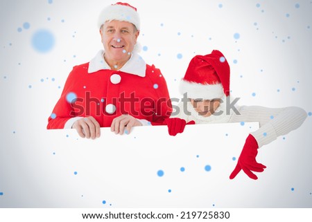 Composite image of festive older couple smiling and holding poster against snow falling