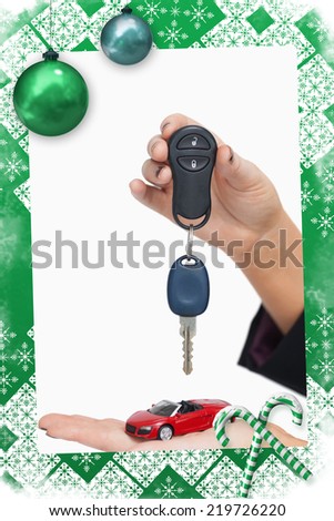 Woman holding key and small car against christmas frame