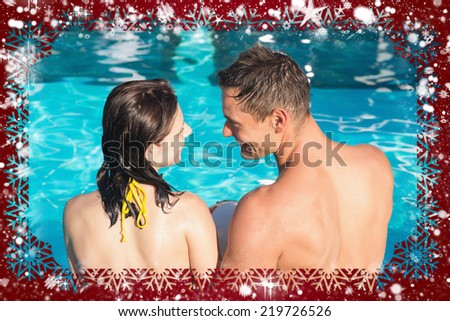 Smiling young couple in swimming pool against snow