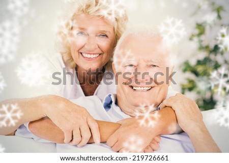 Composite image of happy old couple portrait hugging against snowflakes