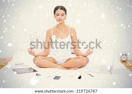 Natural young brown haired model in white pajamas practicing yoga against snow falling