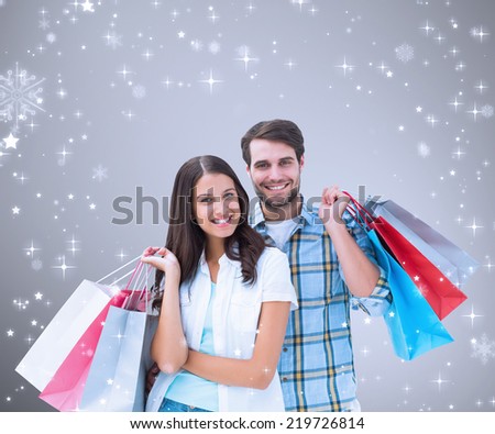 Composite image of happy couple with shopping bags against grey vignette