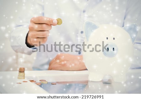 Mid section of a man putting some coins into a piggy bank against snow