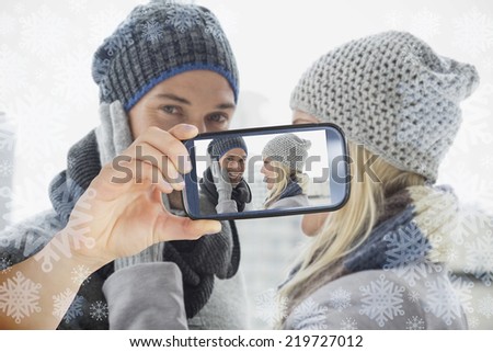 Hand holding smartphone showing photo against snowflake frame