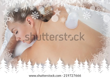 Pretty blonde with vacuum cup on her back against fir tree forest and snowflakes