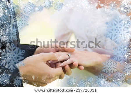 Composite image of snow frame against groom placing ring on brides finger