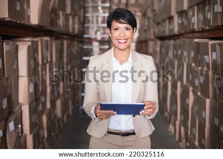 Pretty warehouse manager holding tablet pc in a large warehouse