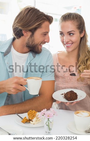Happy couple enjoying coffee and cake at the coffee shop