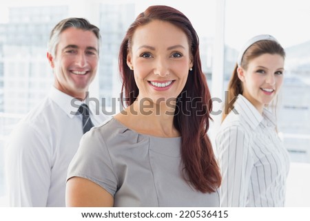 Smiling businessman and her co-workers standing behindwo