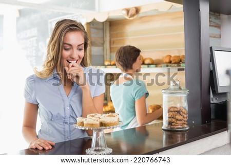 Pretty blonde being tempted by cupcakes at the coffee shop