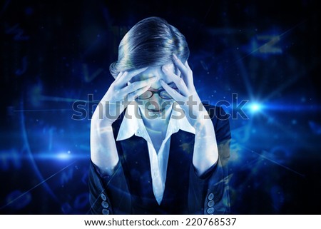 Redhead businesswoman with head in hands against blue background with letters