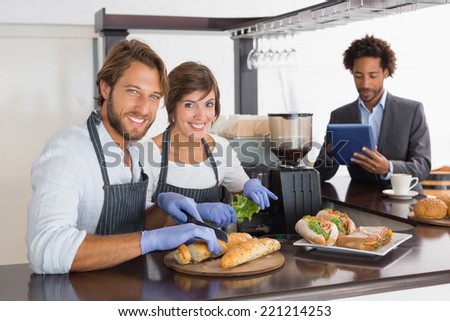 Happy servers preparing sandwiches together at the coffee shop