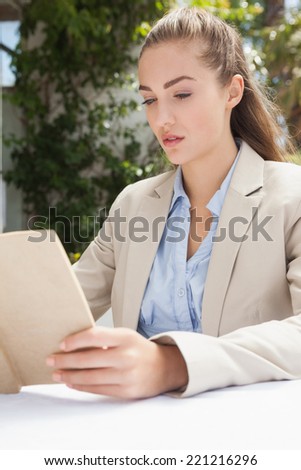 Beautiful businesswoman reading a book outside at the coffee shop