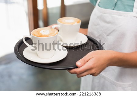 Waitress holding tray with cappuccinos at the coffee shop