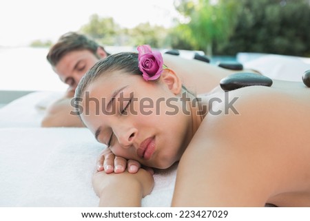 Side view of a young couple enjoying stone massage at health farm