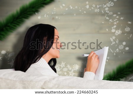 Woman writing down some notes against blurred fir tree branches