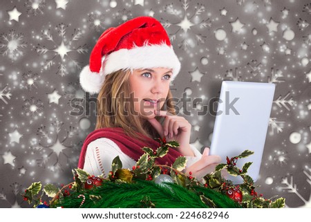 Festive blonde looking at tablet pc against snowflake wallpaper pattern