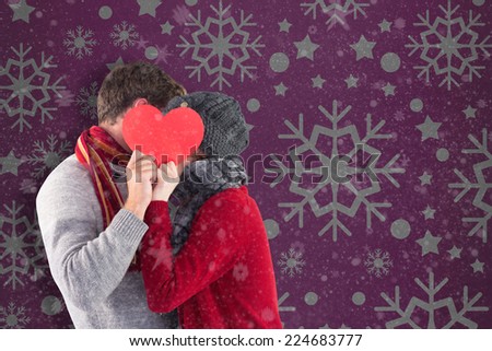 Woman holding a large heart against snowflake wallpaper pattern