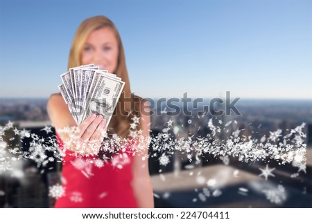 Pretty blonde showing wad of cash against city skyline