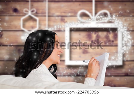 Woman writing down some notes against blurred christmas background