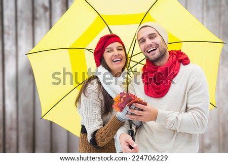 Autumn couple holding umbrella against blurred wooden planks