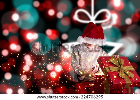 Festive boy opening gift against blurred christmas background