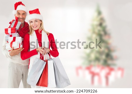 Happy festive couple with gifts and bags against blurry christmas tree in room