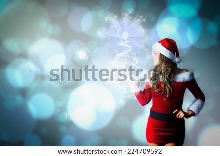 Pretty girl in santa costume holding hand out against light glowing dots design pattern