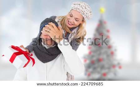 Happy winter couple with gift against blurry christmas tree in room