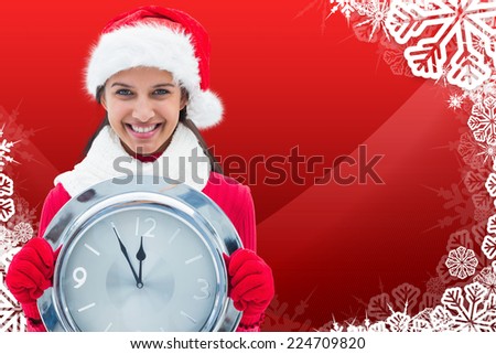 Festive brunette holding clock against christmas themed snow flake frame