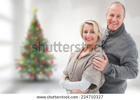 Mature winter couple against blurry christmas tree in room