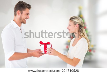 Young couple with gift against blurry christmas tree in room