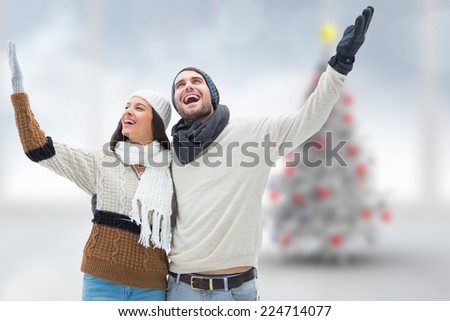 Young winter couple against blurry christmas tree in room