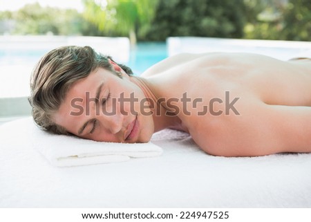 Side view of a handsome young man lying on massage table at spa center