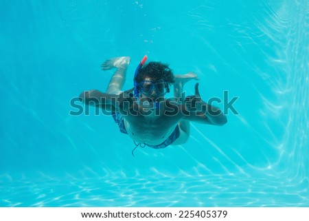 Young man wearing snorkel underwater while gesturing thumbs up
