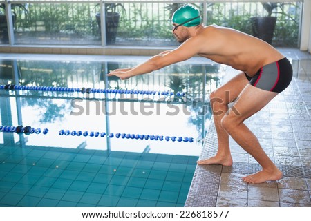 Side view of a fit swimmer about to dive into the pool at leisure center