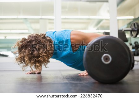 Side view of a young man doing push ups in the gym