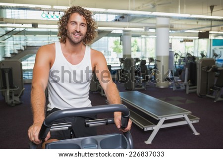 Portrait of a handsome young man working out on exercise bike at the gym