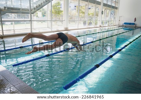 Side view of a fit swimmer diving into the pool at leisure center