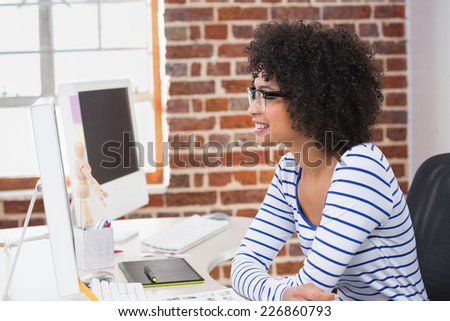 Side view of smiling female photo editor using computer in the office