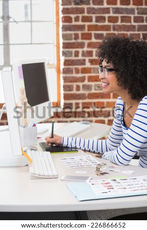 Side view of smiling female photo editor using digitizer in the office