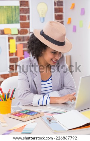 Smiling female interior designer using laptop at office desk